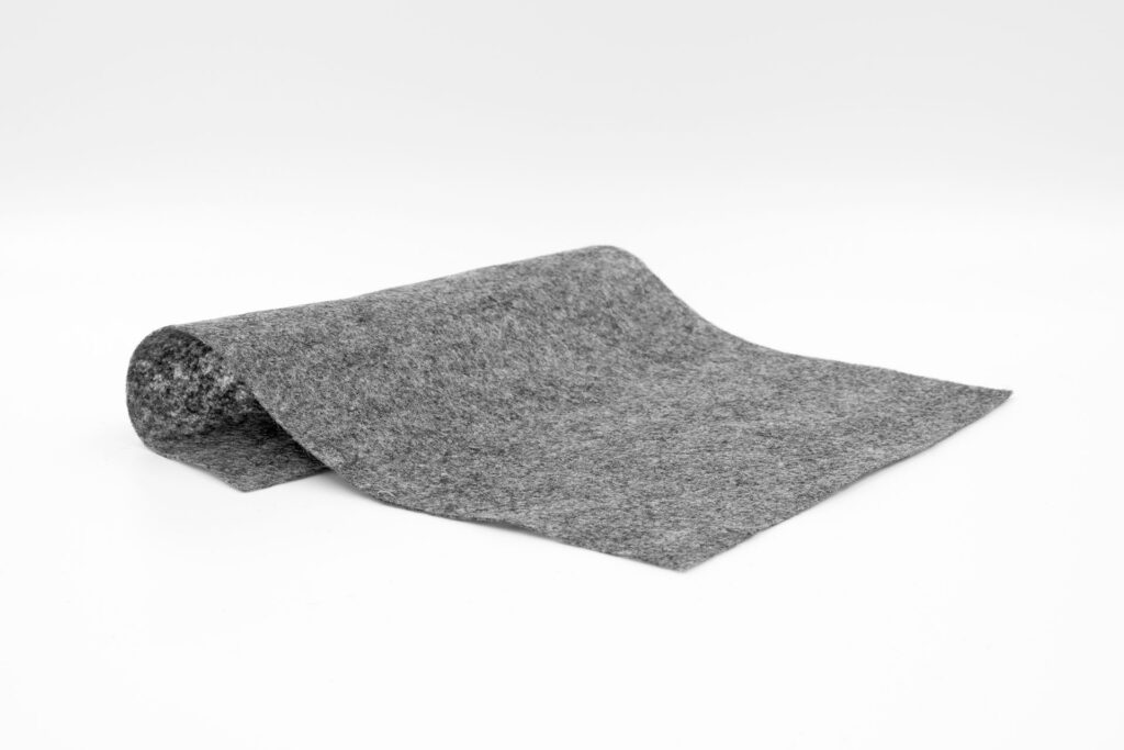 Kawałek materiału geowłókniny GEOLAM PES PRESS 150 ukazujący jej niewielką grubość.